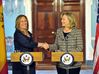 Two women shake hands behind two podiums.