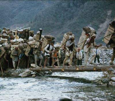 Men cross a bridge made of two logs as they hike to base camp on Mount Everest in 1963 in preparation for an American team to attempt to summit.