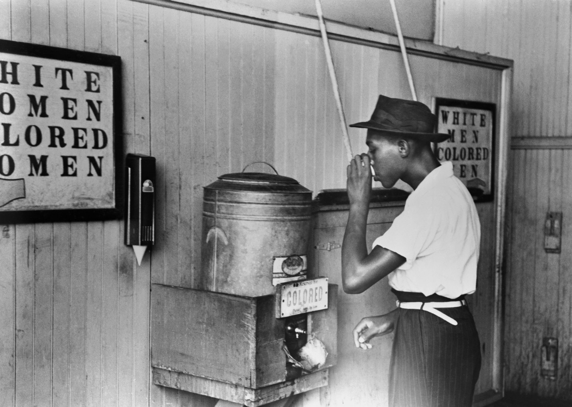 Black man drinking from a "colored only" drinking fountain