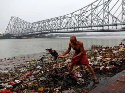 <p>Plastic pollution can hugely damage communities. Here, a&nbsp;man cleans garbage on the banks of the&nbsp;Ganges in Kolkata, India.</p>